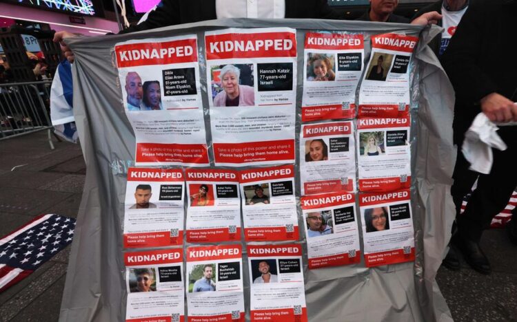 NEW YORK, NEW YORK - OCTOBER 19: A man holds a banner displaying photos of kidnapped Israelis at a rally in Times Square demanding Hamas free Israeli hostages on October 19, 2023 in New York City. Family members of hostages held by Hamas were joined by politicians, members of the Israeli community and supporters as they demanded the release of the men, women, and children that were kidnapped by the militant group during its attack on October 7. The event, which was organized by the Israeli-American Council (IAC) and other Jewish community organizations, also projected the faces of the hostages on 15 billboards and showed holograms of the hostages' families on the rally stage. Israeli officials have reported that Hamas has 199 hostages.   Michael M. Santiago/Getty Images/AFP (Photo by Michael M. Santiago / GETTY IMAGES NORTH AMERICA / Getty Images via AFP)