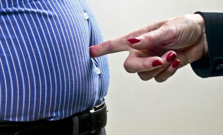 Woman poking man in stomach, mid section