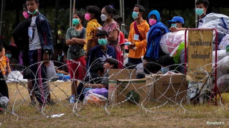 Refugees, who fled a flare-up in fighting between the Myanmar army and ethnic minority rebels, stand at a temporary shelter in Mae Sot district, Tak province, Thailand, December 18, 2021. REUTERS/Athit Perawongmetha