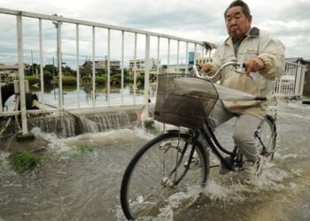 Un Japonais conduit un vélo dans une inondation.