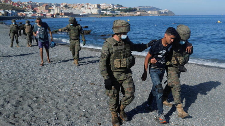 Spanish soldiers help Moroccan citizens at El Tarajal beach, near the fence between the Spanish-Moroccan border, after thousands of migrants swam across this border during last days, in Ceuta, Spain, May 18, 2021. REUTERS/Jon Nazca