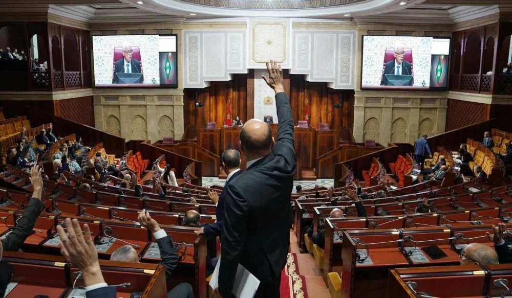 La Chambre des représentants a adopté, ce vendredi 14 novembre, le projet de loi de finances (PLF) 2026 à l’issue d’une séance plénière marathon. Le texte a obtenu 165 voix favorables contre 55, sans abstention, entérinant ainsi le cadre budgétaire qui régira l’action de l’État pour l’année à venir. Le Nouvelliste Maroc +1 Cette adoption intervient après un long parcours en Commission des finances et du développement économique, où la première partie du PLF avait déjà été validée à la majorité, au terme de plus de 90 heures de débats. Au total, 350 amendements ont été déposés, dont 328 pour la première partie et 22 pour la seconde, portant principalement sur les dispositions fiscales et douanières. medi1news.com +1 Le gouvernement, représenté par la ministre de l’Économie et des Finances, Nadia Fettah, et le ministre délégué chargé du Budget, Fouzi Lekjaa, défend un texte présenté comme l’instrument d’une « nouvelle phase » de la dynamique économique nationale. Il s’agit, selon l’Exécutif, de passer d’une logique de simple résilience post-crises à une trajectoire de croissance durable, fondée sur la diversification des sources de richesse, le renforcement de l’attractivité de l’investissement et la consolidation de l’État social. Telquel.ma +2 Lebrief +2 Le PLF 2026 met ainsi l’accent sur le financement des grands chantiers sociaux (généralisation de la protection sociale, santé, éducation), la maîtrise des équilibres macroéconomiques et l’amélioration de l’efficacité de la dépense publique. Il s’inscrit également dans la continuité du Nouveau Modèle de Développement, en cherchant à concilier justice sociale, développement territorial intégré et modernisation de l’économie. Maroc +1 Face à la majorité, les groupes de l’opposition, qui ont massivement voté contre le texte, ont multiplié les amendements et exprimé leurs réserves sur la capacité du budget à répondre pleinement aux attentes sociales dans un contexte de tensions sur le pouvoir d’achat. Leur rejet n’a toutefois pas empêché l’adoption du PLF,